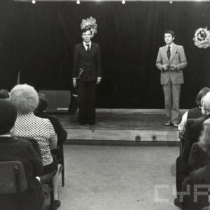 dwóch mężczyzn stoi na scenie, przygląda się im publiczność