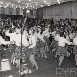 grupa tańczących dzieci na scenie, w głębi widzowie