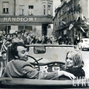 mężczyzna i młoda kobieta w kabriolecie, w głębi budynki