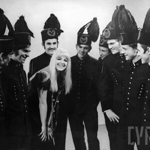 czarno-białe zdjęcie młodej blondynki w otoczeniu grupy górników w strojach galowych