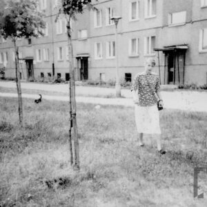 kobieta na spacerze z psem; z tyłu blok z wielkiej płyty