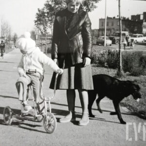 dziewczynka z mamą i psem na spacerze; dziewczynka siedzi na trójkołowym rowerze