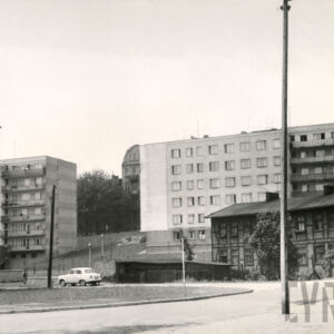 z prawej dwukondygnacyjny dom drewniano-ceglany; w głębi kilkukondygnacyjne bloki mieszkalne