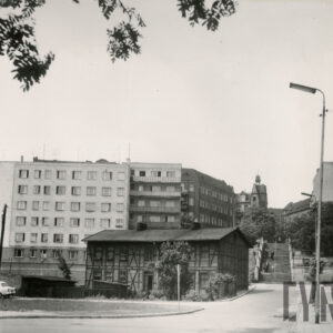 w środku dwukondygnacyjny dom drewniano-ceglany tzw. mur pruski, za nim, na prawo schody, w głębi kilkupiętrowe bloki mieszkalne