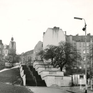 pośrodku betonowe schody otoczone kilkukondygnacyjnymi kamienicami