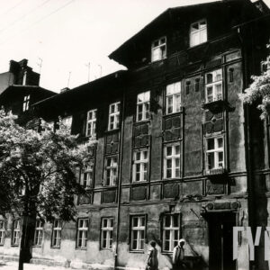 dwupiętrowa kamienica z mieszkalnym poddaszem, przed budynkiem drzewa