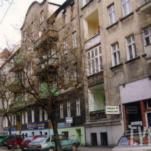 szereg kilkukondygnacyjnych kamienic, przed nimi drzewa, na chodniku zaparkowane samochody