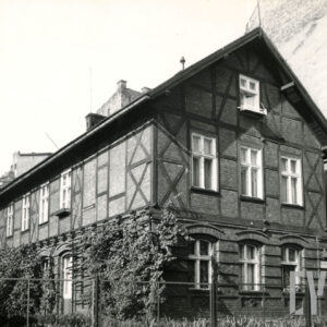 budynek drewniano-ceglany, otoczony płotem