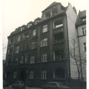 trzypiętrowa kamienica z mieszkalnym poddaszem, przed kamienicą zaparkowane samochody