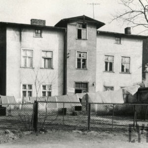 trzykondygnacyjny otynkowany budynek mieszkalny, na pierwszym planie sznur z rozwieszonym praniem