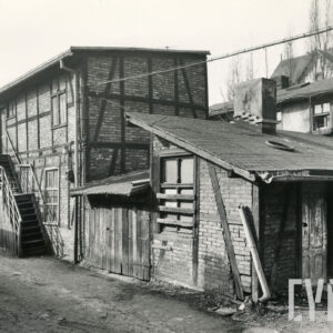 dwukondygnacyjny budynek drewniano-ceglany z zewnętrznymi drewnianymi schodami z drewniano-ceglaną przybudówką