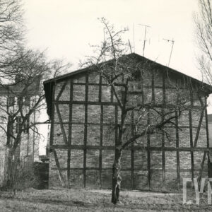 ściana budynku drewniano-ceglanego. wokół niego drzewa bez liści