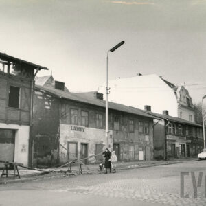 zaniedbane, dwukondygnacyjne proste budynki w trakcie rozbiórki, na pierwszym planie brukowana ulica