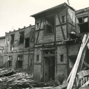 dwukondygnacyjny, drewniano-ceglany budynek w trakcie rozbiórki, przy nim leżące deski i cegły