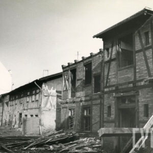 dwukondygnacyjne, zaniedbane budynki, z prawej budynek drewniano-ceglany w trakcie rozbiórki