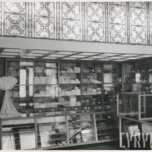 półki z poskładanymi na nich ubraniami, przed nimi lada