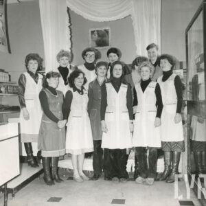 kilkanaście kobiet w fartuszkach stoi w dwóch rzędach w sklepie i pozuje do zdjęcia