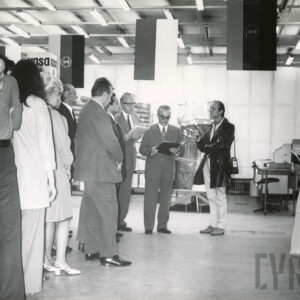 duży sklep, pośrodku ludzie, w środku mężczyzna czyta tekst, obok niego mężczyzna z mikrofonem