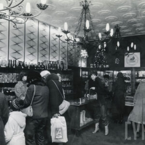 wnętrze sklepu, na półkach ceramika i szkło, przy ladach stoją kupujący, z sufitu zwisają metalowe żyrandole