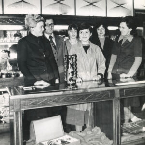 grupa kobiet z mężczyzną stoi przy ladzie na tle półek z porcelaną