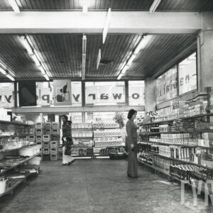 wnętrze sklepu z półkami i ustawionymi na nich towarami, w środku dwie osoby