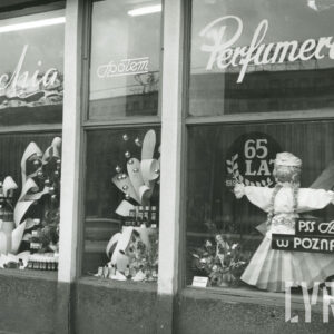 dekoracja w witrynie okna złożona z artykułów drogeryjnych i kukły przedstawiającej dziewczynę