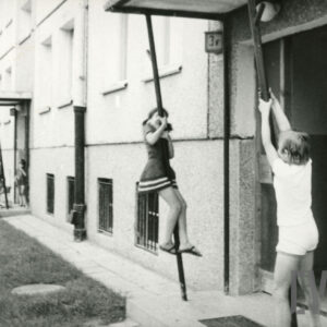 dziewczynki bawiące się przed klatką bloku z wielkiej płyty