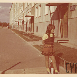 dziewczynka w sukience stojąca na tle bloku z wielkiej płyty