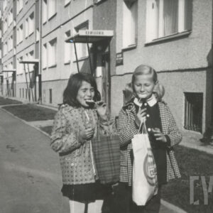 dziewczynki z lizakami, spacerujące na tle bloków z wielkiej płyty