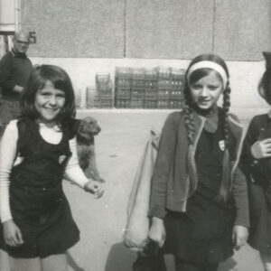 dziewczynki w mundurkach szkolnych, stojące na tle bloku z wielkiej płyty