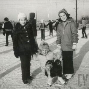 dzieci w ubraniach zimowych jeżdżące na łyżwach po osiedlowym lodowisku