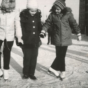 dzieci w ubraniach zimowych jeżdżące na łyżwach po osiedlowym lodowisku