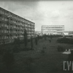 trawnik między blokami z wielkiej płyty, w oddali dźwig budowlany