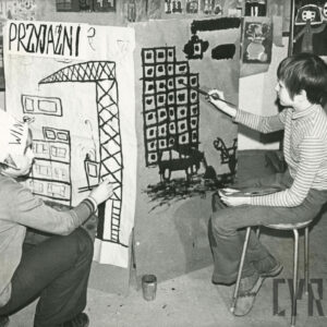 dwóch chłopców malujących prace w czasie zajęć plastycznych; w tle na ścianach wiszą liczne rysunki i prace plastyczne