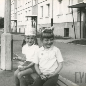 dwie dziewczynki siedząca na ławce przed blokiem z wielkiej płyty