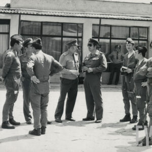 grupa mężczyzn w mundurach wojskowych, w głębi budynek z dużymi oknami