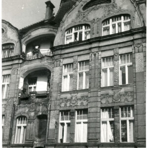 fragment ściany frontowej kamienicy z oknami i balkonami z bogatą dekoracją architektoniczną