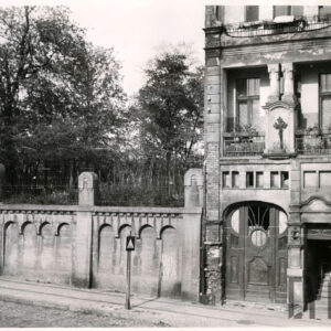 fragment dwóch dolnych kondygnacji kamienicy wraz z wejściem do niej, z lewej ozdobny mur