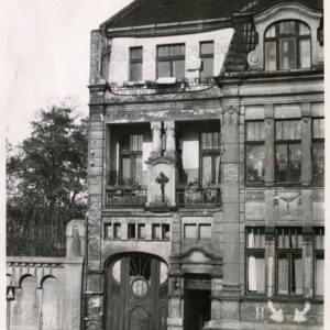 fragment kamienicy wraz z wejściem do niej, z lewej ozdobny mur