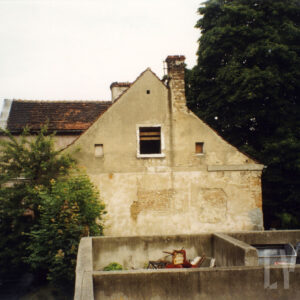 budynek z odpadającym tynkiem, skośnym dachem i kominem