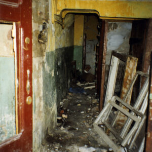 zniszczone pomieszczenie, na podłodze porozrzucany gruz, cegły i fragmenty ram okiennych, na ścianach łuszcząca się o odpadająca farba