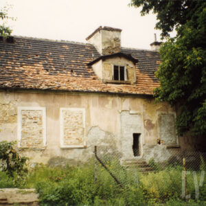 budynek z zamurowanymi oknami i wejściem,, na ścianach odpadający tynk