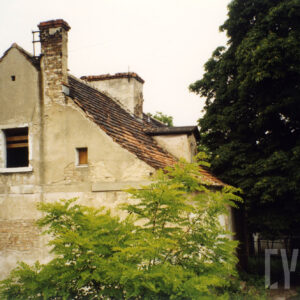 budynek z odpadającym tynkiem, skośnym dachem i kominem