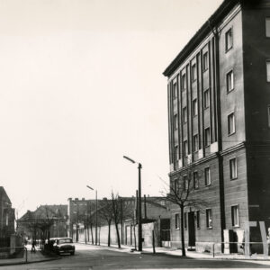 asfaltowa ulica, po obu stronach kilkukondygnacyjne budynki