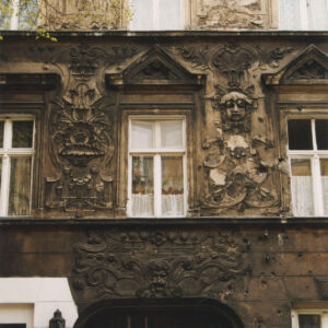 fragment elewacji czterokondygnacyjnej kamienicy z bogatą dekoracją rzeźbiarską