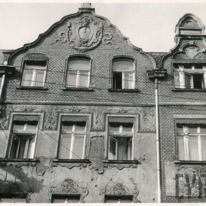 ostatnie dwie kondygnacje kilkukondygnacyjnej narożnej kamienicy z dekoracją rzeźbiarską na szczycie 