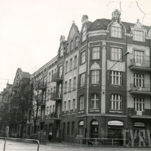 przy ulicy rząd kilkukondygnacyjnych kamienic, z prawej, na pierwszym planie pięciokondygnacyjna kamienica narożna ze zdobionymi szczytami