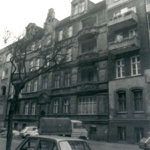 trzypiętrowa kamienica z przyziemiem i mieszkalnym poddaszem, po obu stronach ulicy zaparkowane samochody