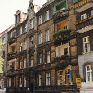 trzypiętrowa kamienica z przyziemiem i mieszkalnym poddaszem, przed nią zaparkowane samochody