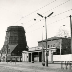 brama zakładu, z lewej konstrukcja zwężającego się ku górze szerokiego komina